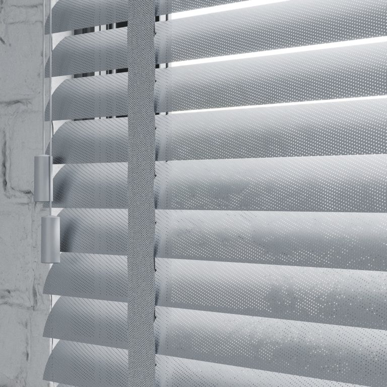 Perforated metal venetian blinds with fabric ladder tape against concrete wall, backlit LED strip lighting between slats.